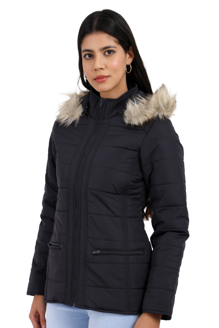 A woman in a standing side pose, wearing Trufit’s dark grey Matte Quilted Jacket with Horizontal Pockets, zip closure, a removable hood and blue jeans.